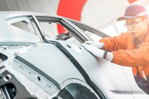 worker assessing the car frame damage for a car frame repair