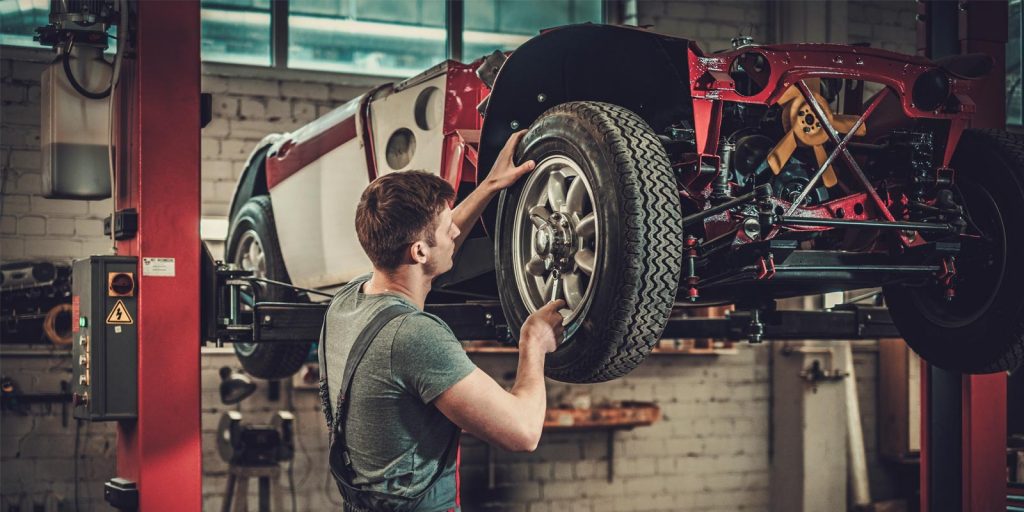 Car mechanic working with car in the air