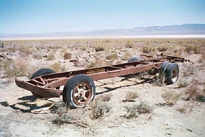 an old rusted truck frame in the middle of a desert