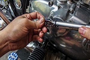 hands fixing a custom motorcycle using tools