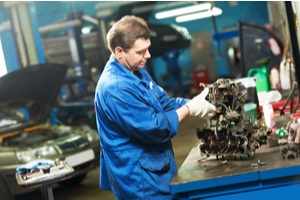mechanic worker works with engine or gearbox during automobile car maintenance at repair service station