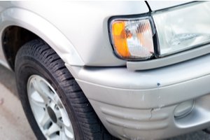 Multiple minor bents near the headlight of a car