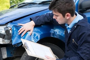 insurance agent inspecting car after collision